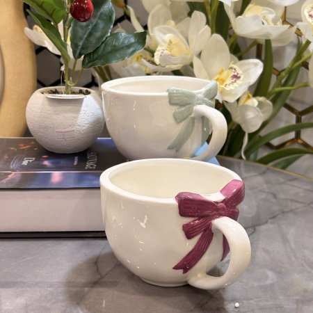 مج سيراميك أبيض مع مقبض دائري مزين بفيونكة